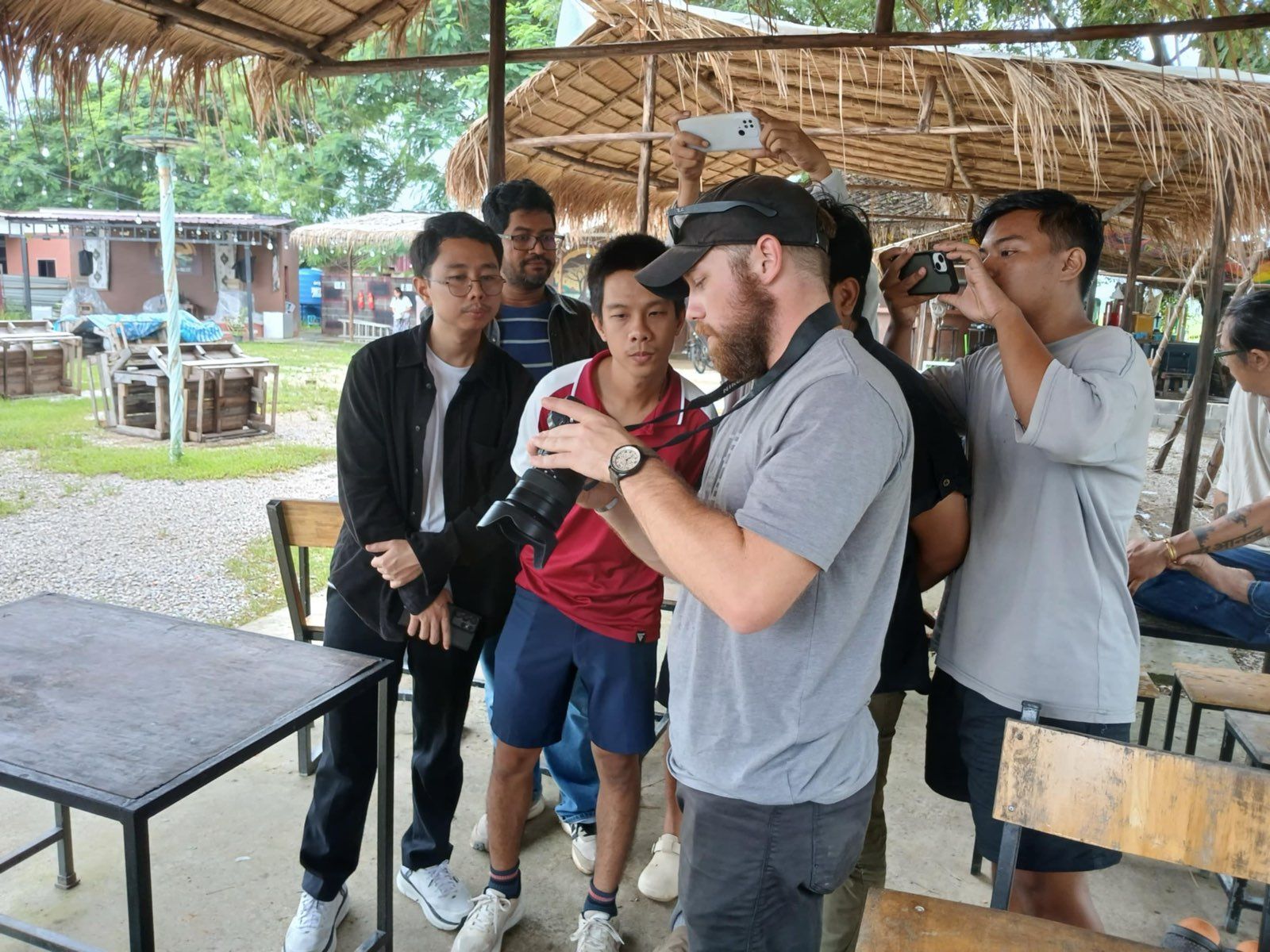A trainee looks through a camera viewfinder while an instructor guides the camera in his hands