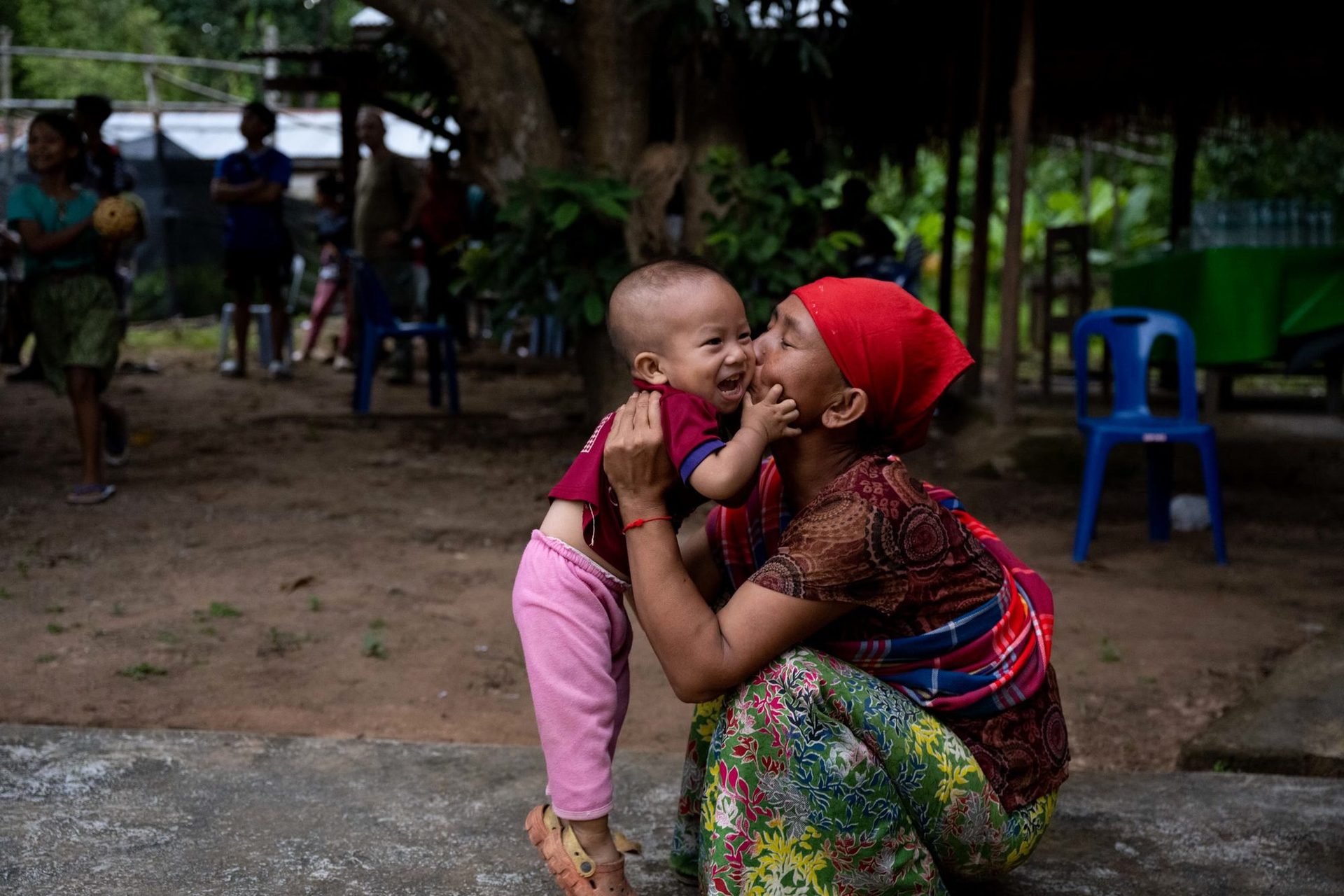 A grandmother holding a small child in a village in Burma, 2025