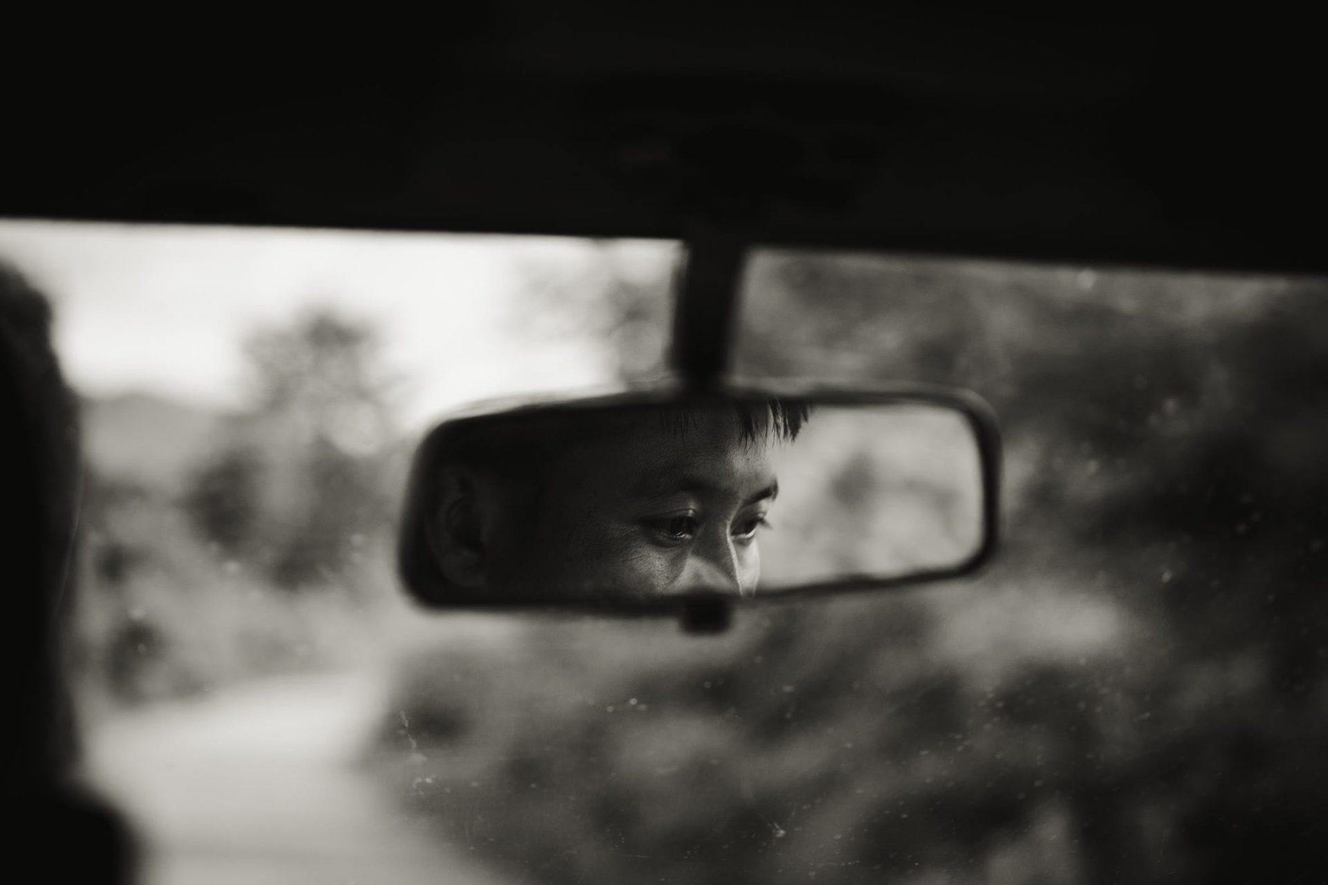 A child's eyes reflected in the rear-view mirror of a moving vehicle