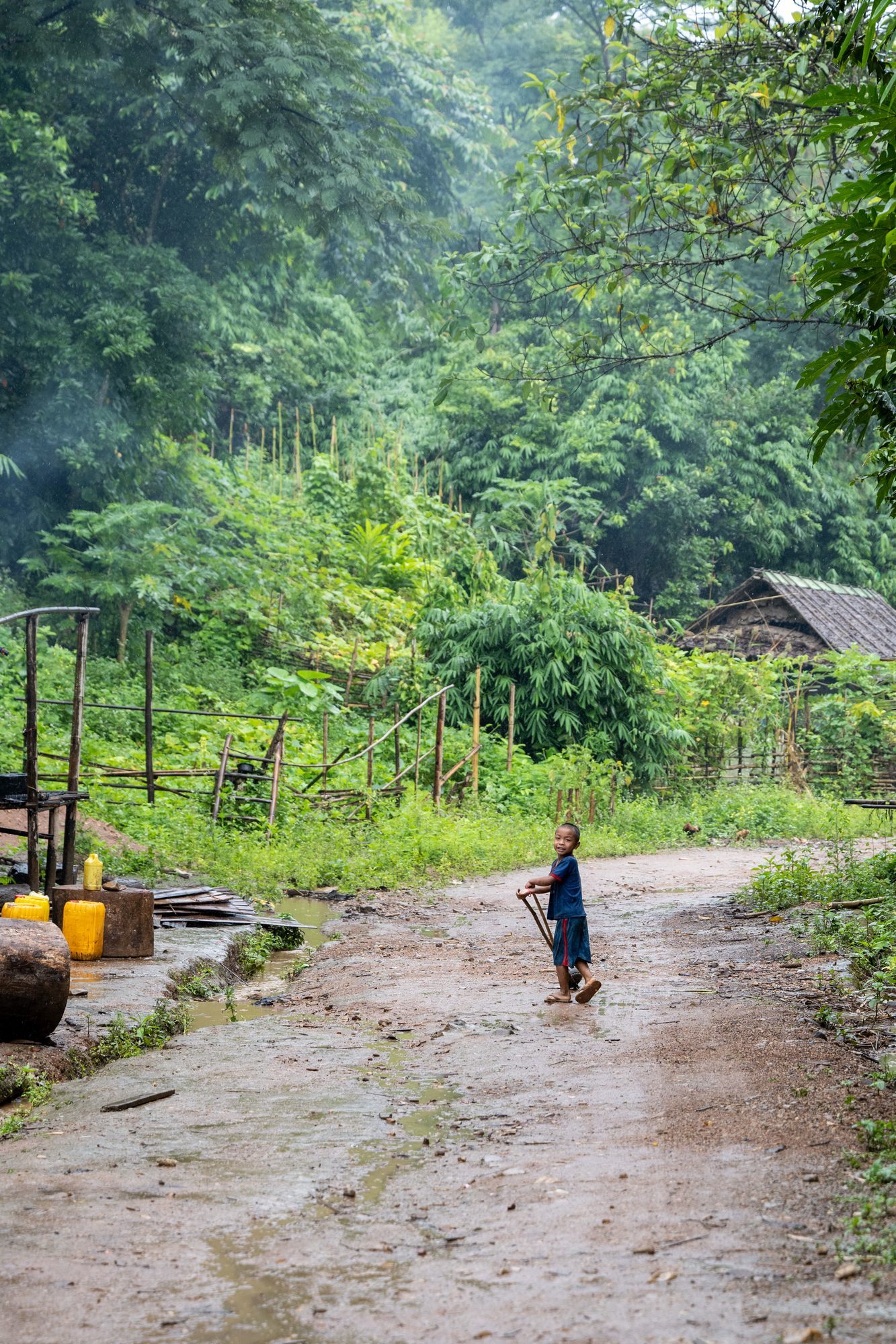 A village path after rain, a small figure walking in the distance