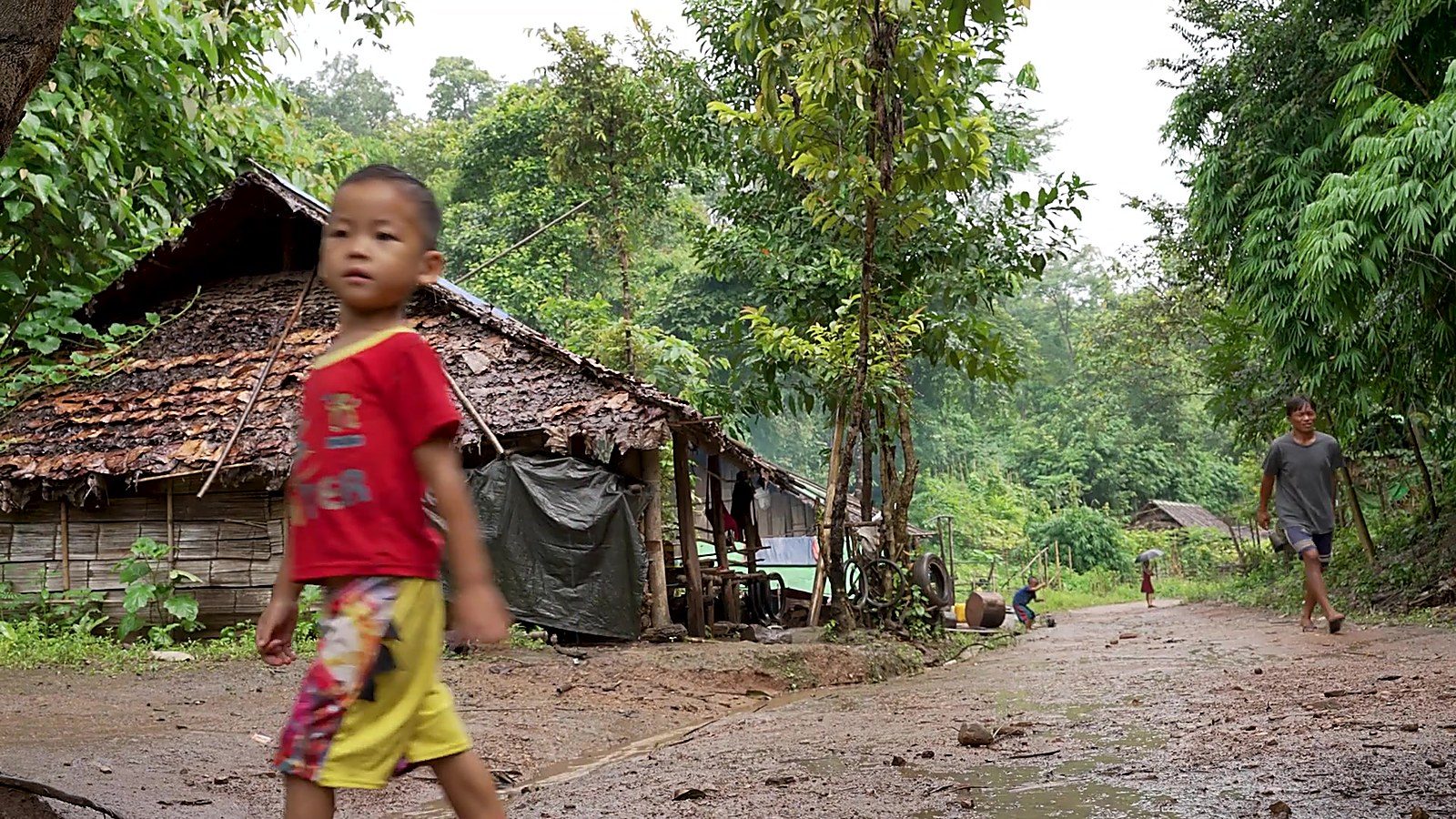 A boy walking through a village in Burma